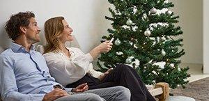 Gezin bij de kerstboom die gebruikmaken van de bediening van KlikAanKikUit