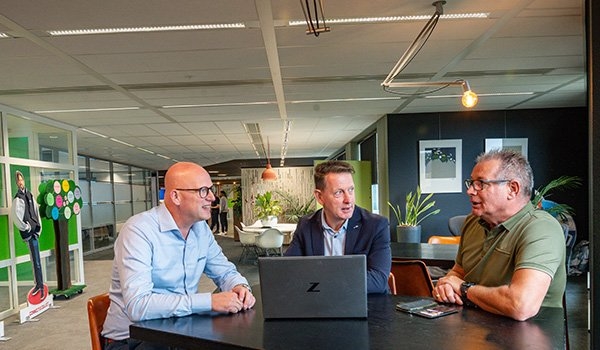 De betrokkenen zitten rond een tafel met een laptop. 