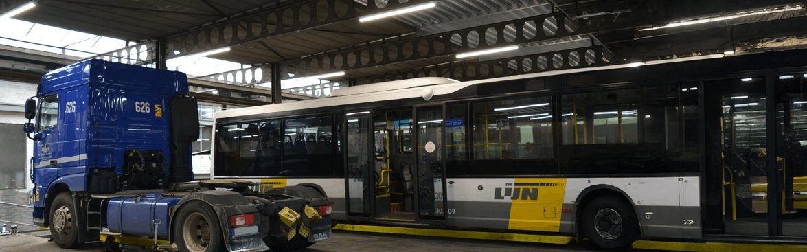Vrachtwagen en lijnbus staan overdekt in een grote loods verlicht met de Opple EcoMax verlichting