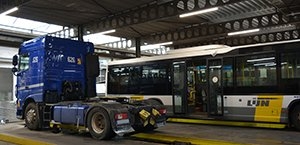 Vrachtwagen en lijnbus staan overdekt in een grote loods verlicht met de Opple EcoMax verlichting