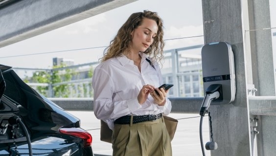 Een vrouw die haar auto is aan het laden in een garage