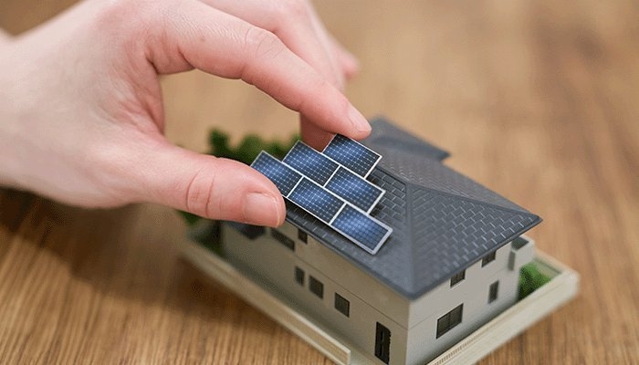 Op een miniatuurmodel van een huis worden zonnepanelen gelegd