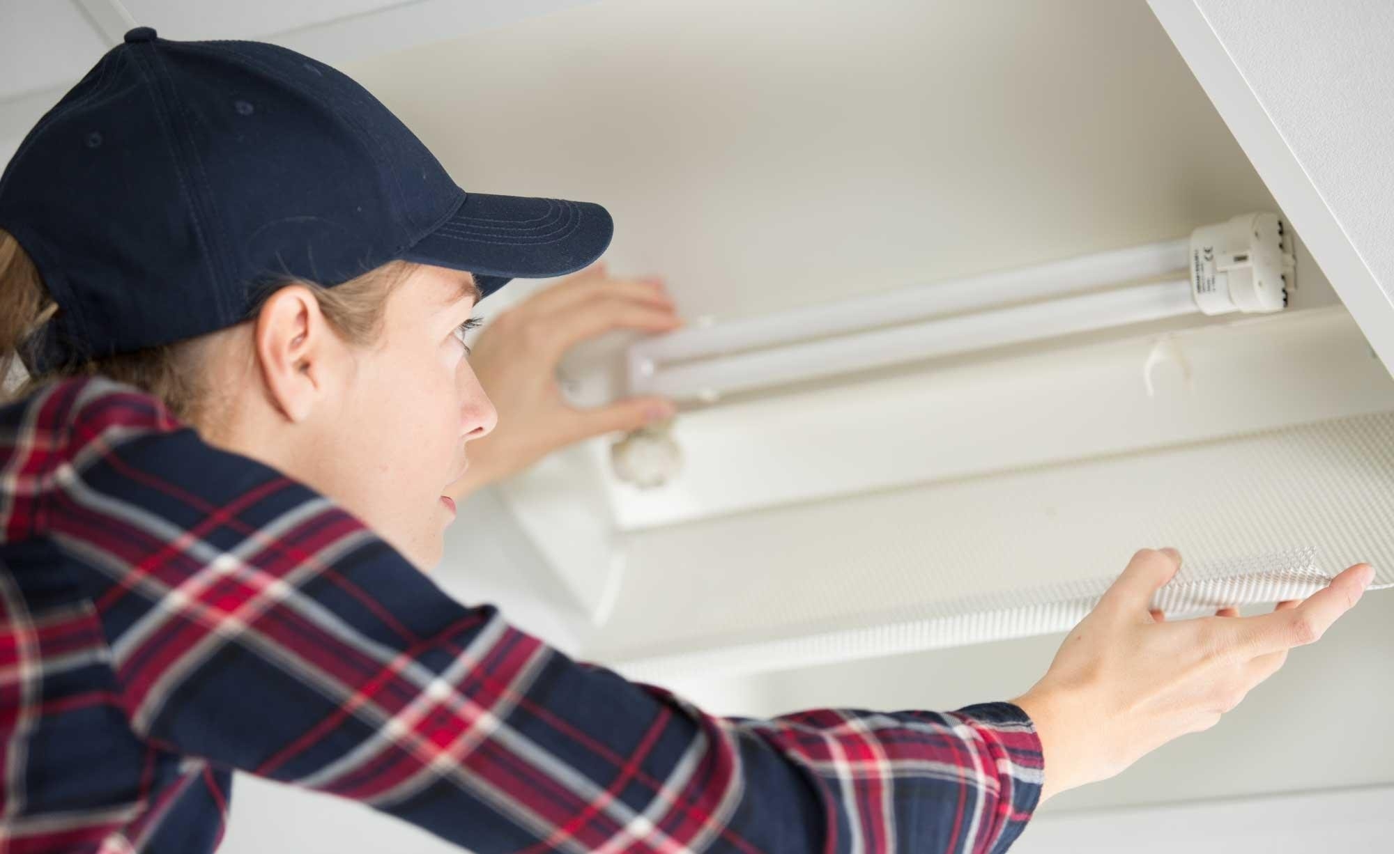 Elektrikerin beim Lampentausch